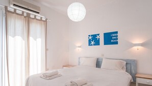 Une chambre d’hôtel avec un lit, deux lampes fixées au mur, un luminaire au plafond et une fenêtre avec des rideaux.