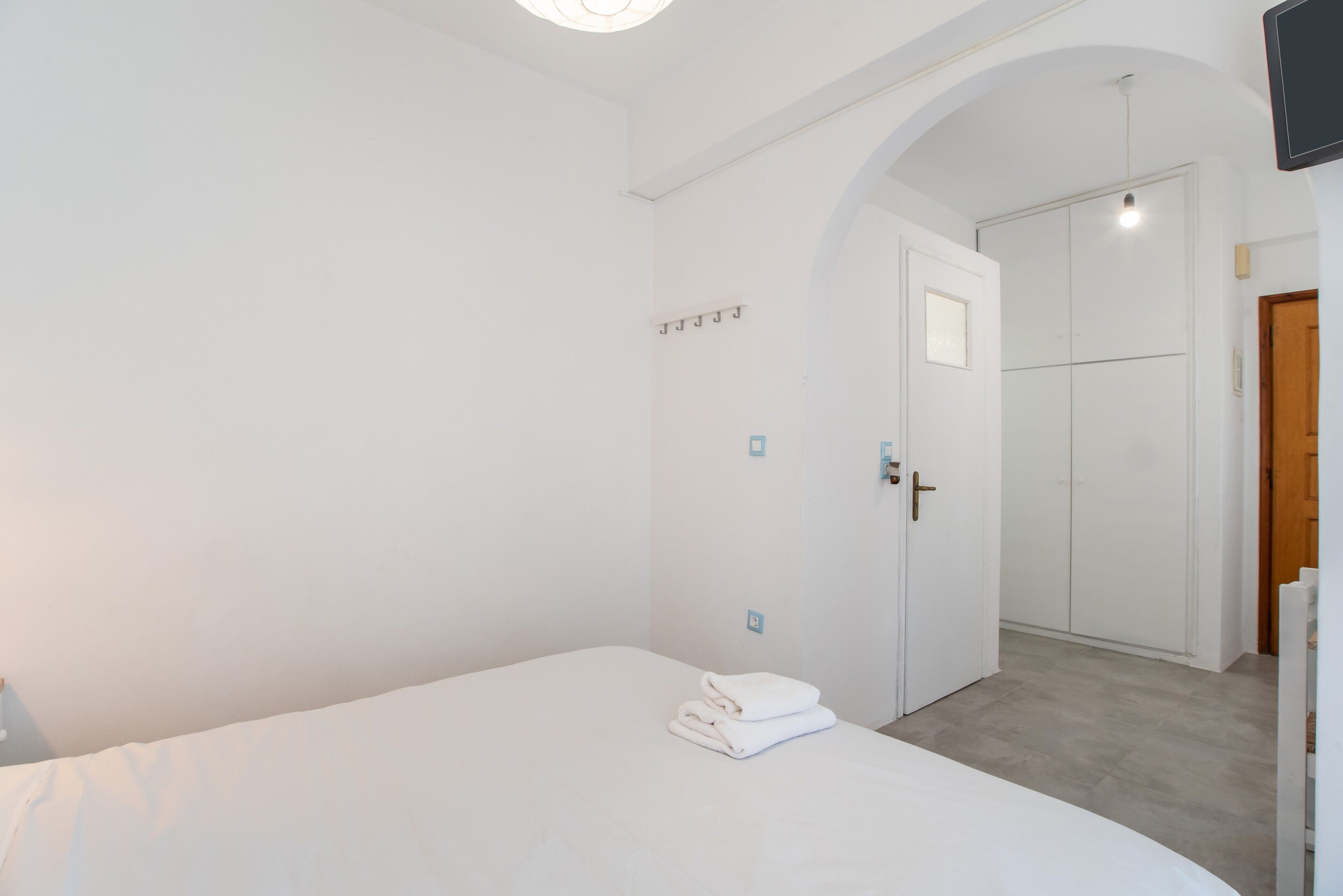 Een slaapkamer met een bed, een kledingkast en een deur naar een andere kamer.