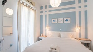 A hotel room with a bed, nightstands, a mirror, and a window with curtains. - Studio Apartment 'Livadia Seaside Studios 12' with Shared Terrace, Wi-Fi and Air Conditioning (Paros)