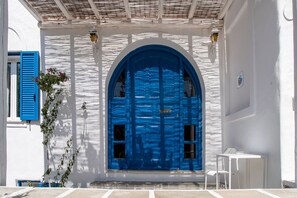 Ein weißes Gebäude mit einer blauen Rundbogen-Tür, einem kleinen weißen Tisch und einem Blumentopf.