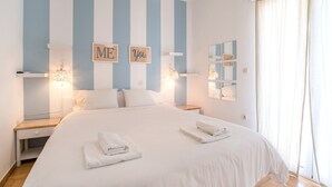 A bedroom with a large bed, two bedside tables, wall-mounted light fixtures, and a window with curtains. - Studio Apartment 'Livadia Seaside Studios 14' with Shared Terrace, Wi-Fi and Air Conditioning (Paros)