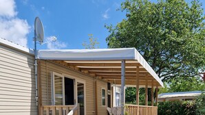 A mobile home with a porch, outdoor seating, and a satellite dish.