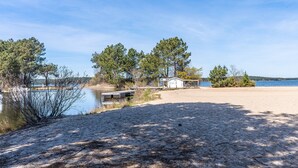A beach with a small building labeled 'SHI CLUB' and a dock extending into a calm body of water.