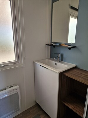 A bathroom with a white sink, a mirror above it, and a window to the left. - 'Mobilehome Familial' with Shared Pool, Garden & Wi-Fi (Gastes)