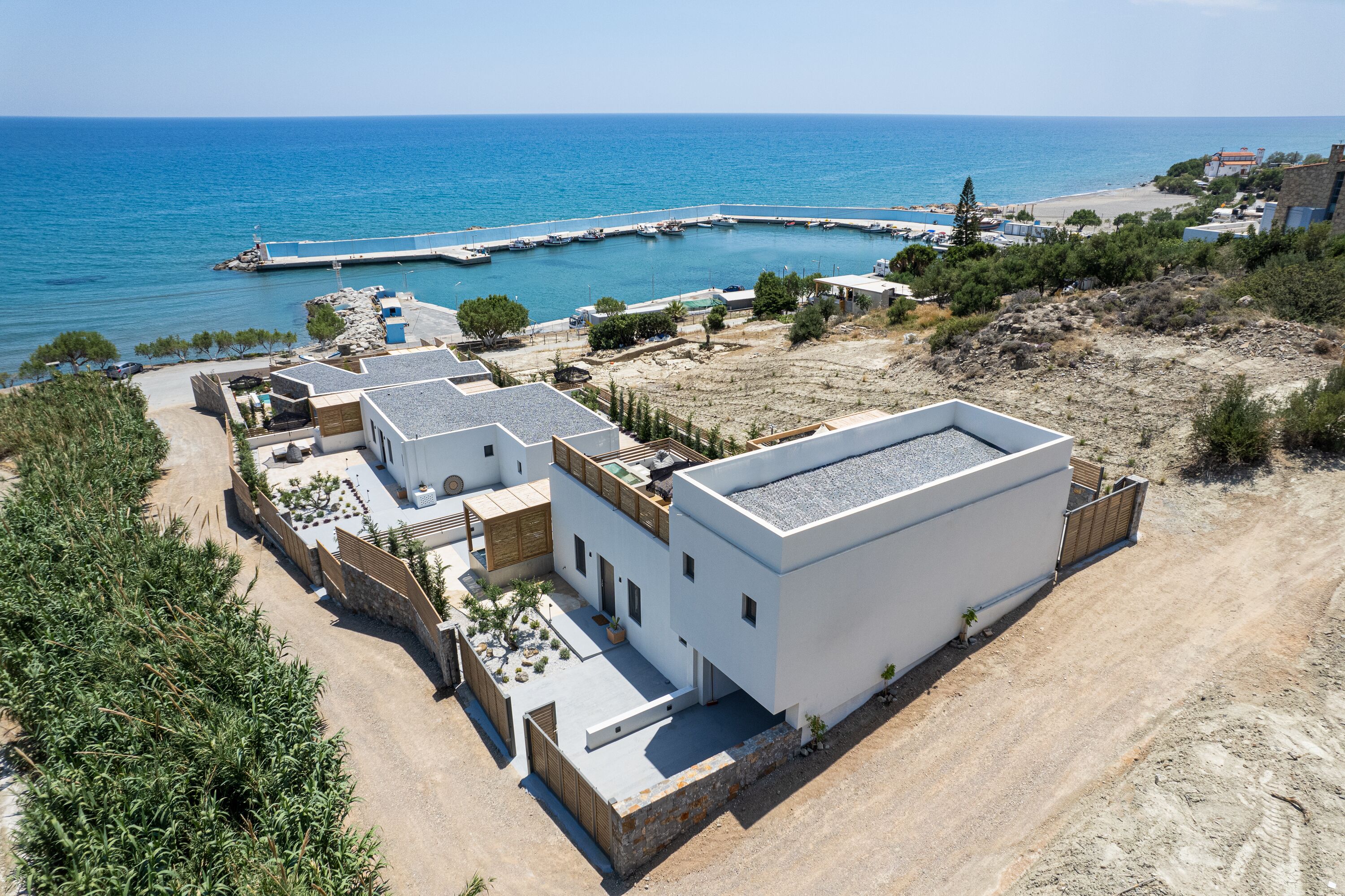 A coastal property with multiple buildings, a sandy beach, and a clear view of the sea.