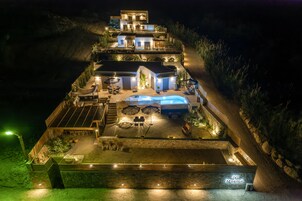 Un hotel de varios pisos con piscina, mobiliario exterior y un muro de contención de piedra.