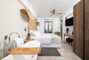 Una habitación de hotel moderna con cama, escritorio, ducha y vistas al mar.