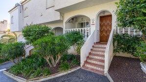 A building with a white facade, a wooden door, and a staircase leading to an entrance. - Bungalow 'Villa Matías' with Sea View, Wi-Fi and Air Conditioning (Gran Alacant)