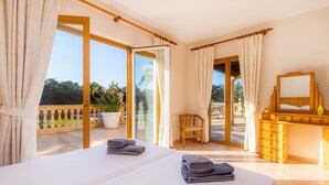 A hotel room with two beds, a wooden dresser, a chair, and a balcony with potted plants. - Villa 'Berna' with Lake View, Wi-Fi and Air Conditioning (Alcudia)