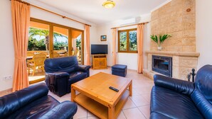 A living room with leather sofas, a wooden coffee table, a TV, and a fireplace. - Villa 'Berna' with Lake View, Wi-Fi and Air Conditioning (Alcudia)