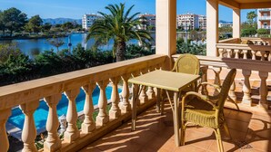A balcony with a view of a lake, a table, and wicker chairs. - Villa 'Berna' with Lake View, Wi-Fi and Air Conditioning (Alcudia)