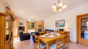 A dining area with a wooden table set for four, a sofa, a television, and a fireplace. - Villa 'Berna' with Lake View, Wi-Fi and Air Conditioning (Alcudia)