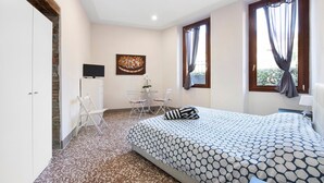 Ein Schlafzimmer mit einem Bett, einem Schreibtisch mit Stuhl, einem Fernseher und einem Bild an der Wand.