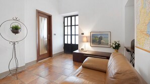 Ein Zimmer mit einer Ledersofa, einem kleinen Tisch mit Lampe, einer Karte an der Wand und einer Tür mit Fenster.