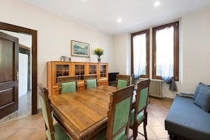 A dining area with a wooden table and chairs, a cabinet with glass doors, and a sofa.