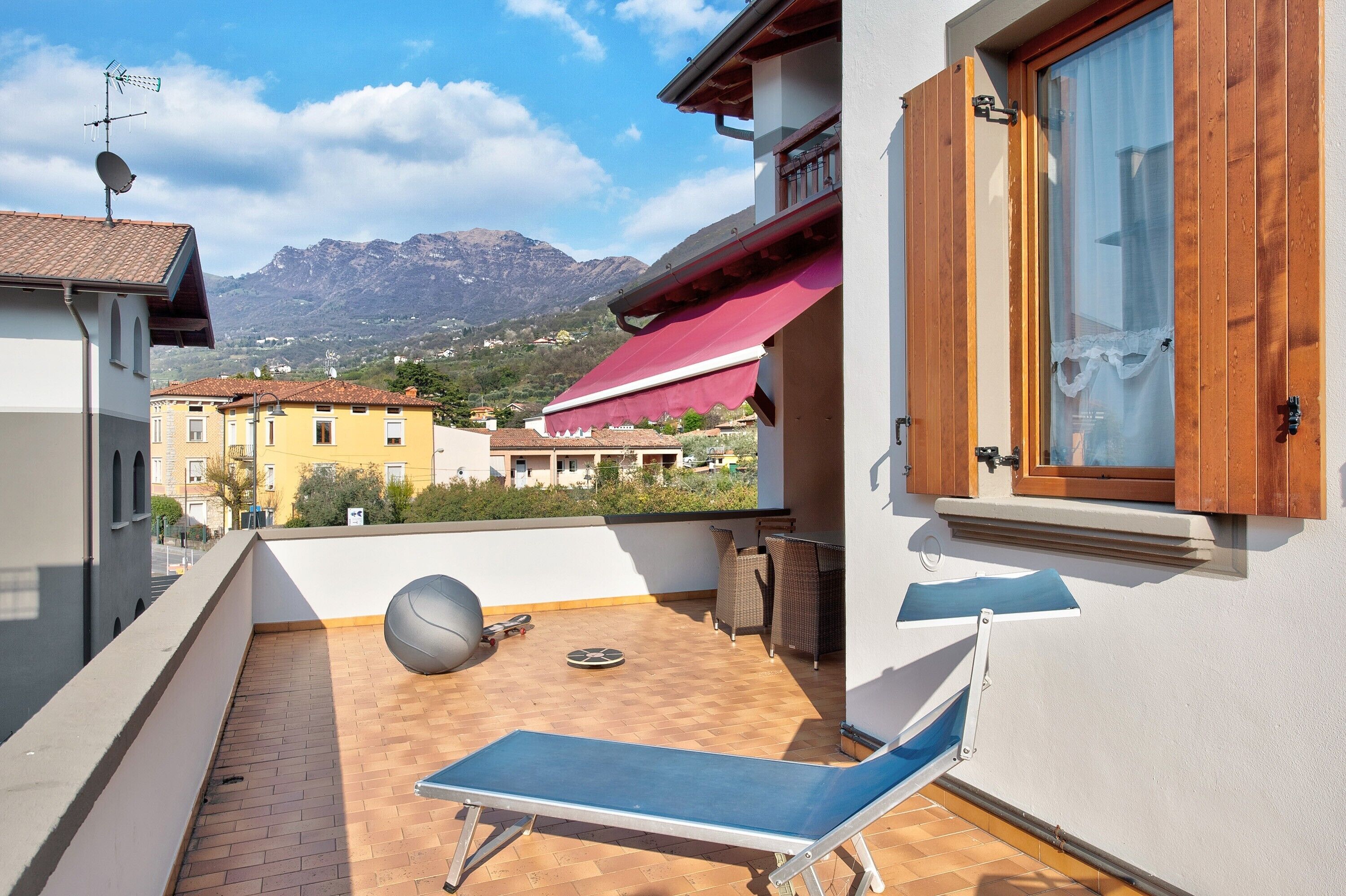 Ein Balkon mit Liegestuhl, Ball und Tisch.