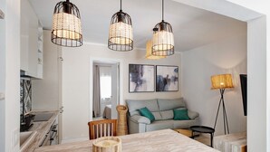 Una cocina moderna con armarios blancos, una mesa de comedor y un sofá en la sala de estar.