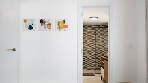 Un dormitorio con cama, una mesita redonda y una puerta que da a un baño con ducha de azulejos.