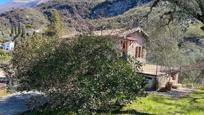 A rustic house with a stone facade, surrounded by lush greenery and mountains in the background. - Apartment 'Olive Grove House' with Lake View, Private Terrace and Shared Garden (Malcesine)