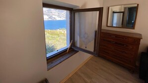 A room with a large window, a wooden dresser, and a mirror on the wall. - Apartment 'Olive Grove House' with Lake View, Private Terrace and Shared Garden (Malcesine)