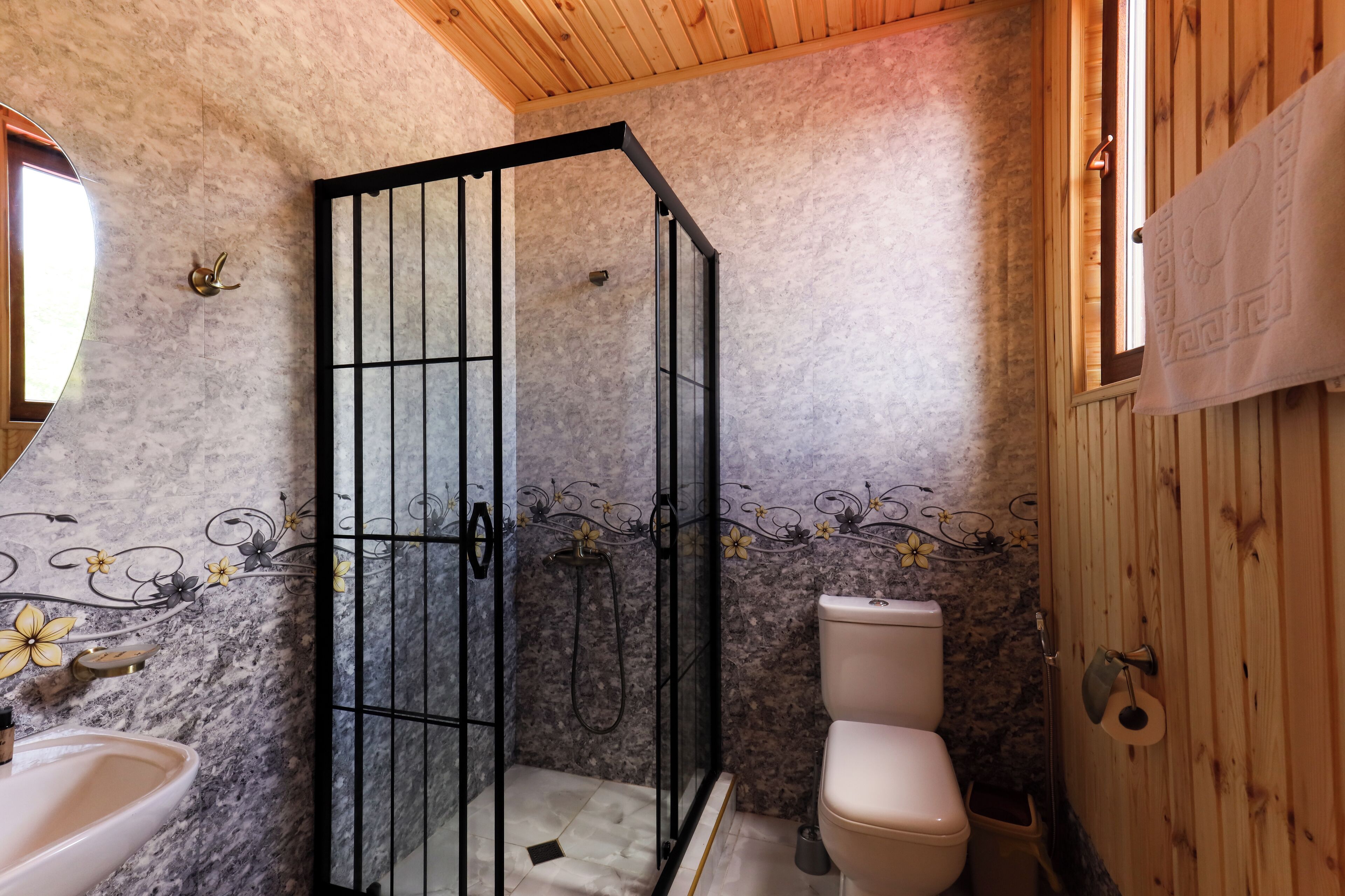 A bathroom with a shower enclosure, toilet, and sink.