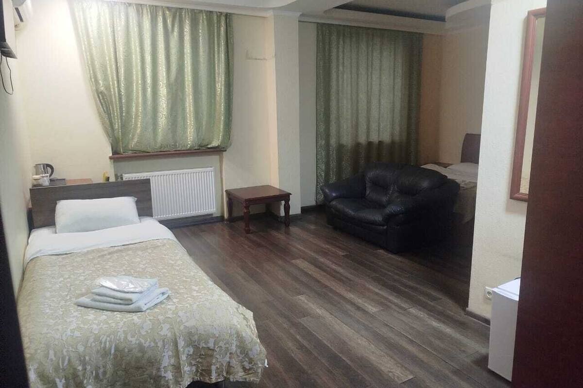 Ein Hotelzimmer mit Bett, kleinem Tisch, Ledersofa und Heizkörper.