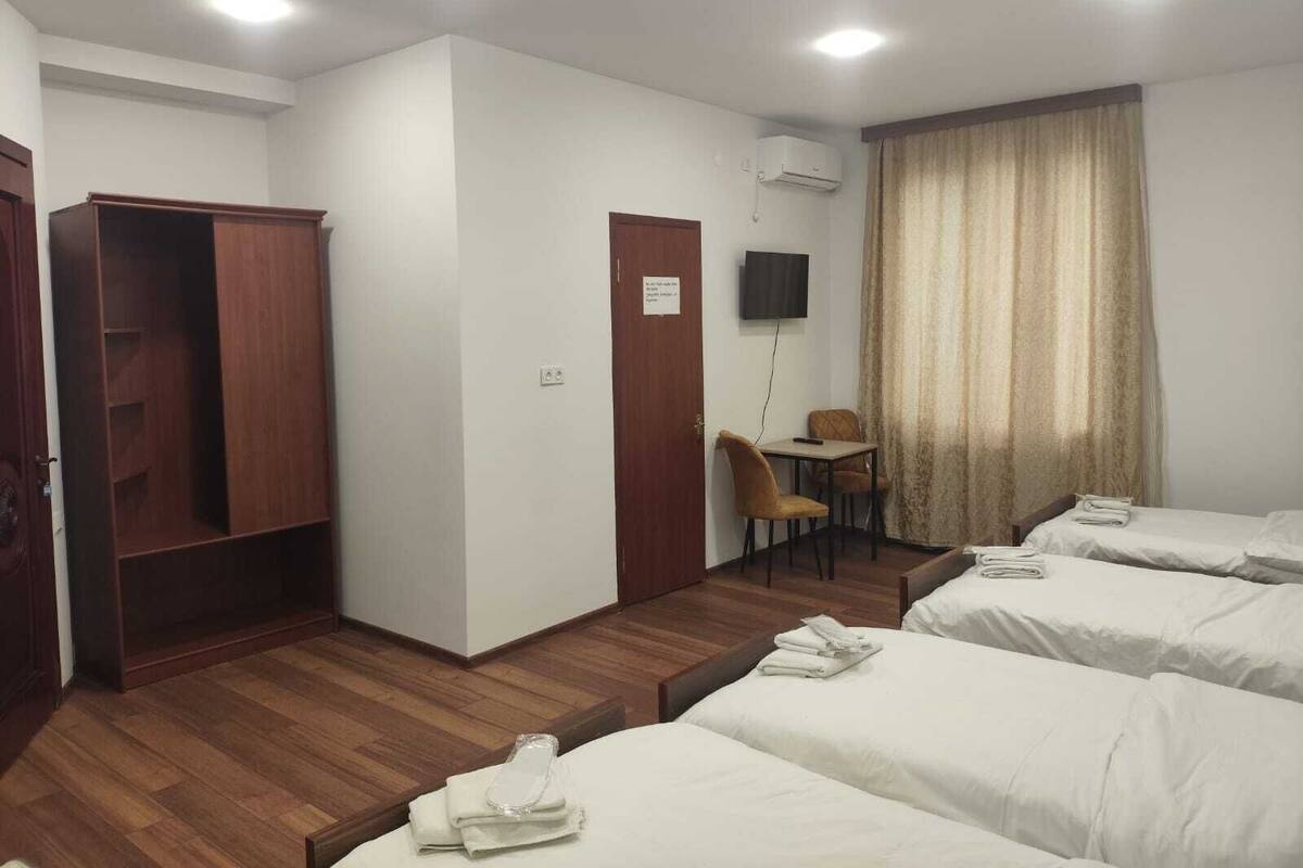 Ein Hotelzimmer mit zwei Betten, einem Schreibtisch, einem Stuhl, einem Kleiderschrank und einer Klimaanlage.