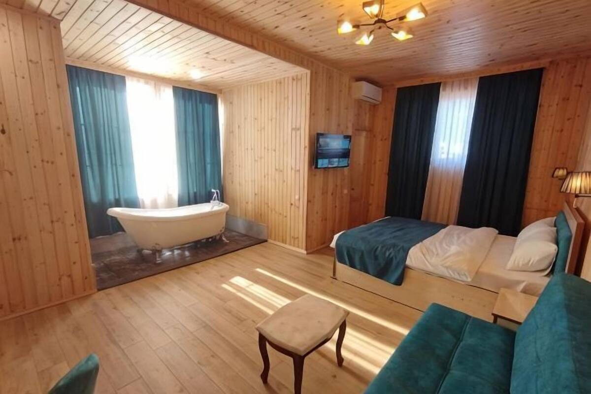 Ein holzgetäfelter Raum im Chalet-Stil mit Badewanne, Bett, Fernseher und kleinem Tisch.