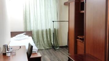 Quarto de hotel com uma cama, uma escrivaninha com cadeira, guarda-roupa e closet.