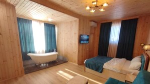 A wooden cabin room with a bathtub, a bed, a small table, and a TV. - Aeetes Palace  (Kutaisi)