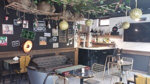 Een bar met een toonbank, krukken en een zithoek met een bank en stoelen.