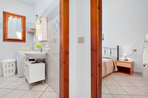 Une salle de bain avec un lavabo, un miroir et un petit meuble de rangement.