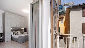 Ein Schlafzimmer mit Bett, Kleiderschrank und einem Balkon mit Geländer.