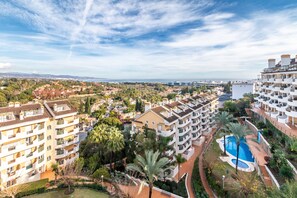 A residential area with multi-story buildings, a swimming pool, and a view of the sea.