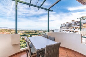 A balcony with a table and chairs, overlooking a cityscape.