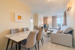 A modern living room with a dining table, sofa, and TV.