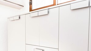 Ein weißer Kleiderschrank mit mehreren Schubladen und einem eckigen Spiegel darüber.