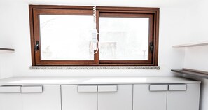 Una cocina con ventana, armarios blancos y una encimera.