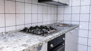 Eine Küche mit Gasherd, Spüle und einer Marmorarbeitsplatte.