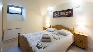 A bedroom with a bed, two bedside tables with lamps, a wall-mounted artwork, a window, and a radiator. - Apartment 'Charmant 3 Etoiles' with Mountain View, Private Terrace and Wi-Fi (Courchevel)
