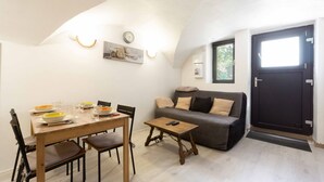 A dining area with a wooden table set for four, a sofa, and a small table with a remote control. - Apartment 'Charmant 3 Etoiles' with Mountain View, Private Terrace and Wi-Fi (Courchevel)
