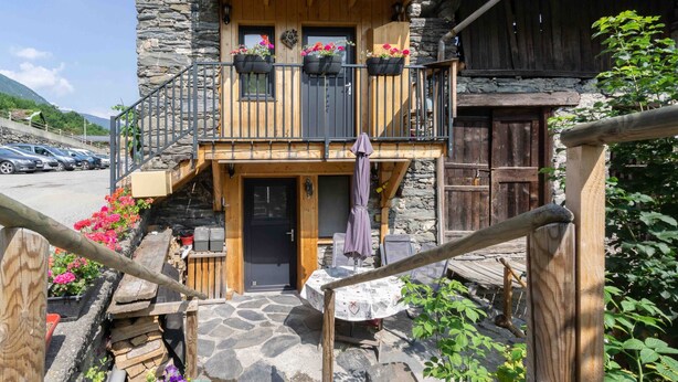 A rustic building with a stone facade, wooden balconies, and a staircase leading to the entrance. - Apartment 'Charmant 3 Etoiles' with Mountain View, Private Terrace and Wi-Fi (Courchevel)