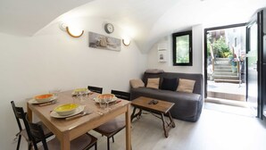 A dining area with a table set for four, a sofa, and a staircase leading outside. - Apartment 'Charmant 3 Etoiles' with Mountain View, Private Terrace and Wi-Fi (Courchevel)