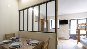 Un coin repas avec une table dressée pour quatre personnes, une chaise en bois et un téléviseur fixé au mur.