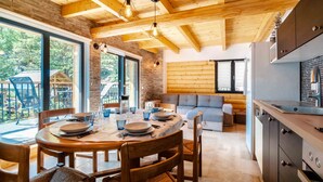 Eine moderne Küche mit Holzausstattung, ein Essbereich mit rundem Tisch und Stühlen sowie Blick ins Freie.