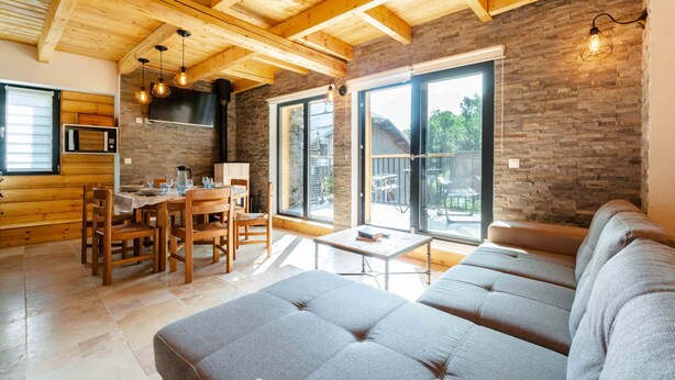Ein modernes Interieur mit Holzboden, Steinwand und einem Essbereich mit Tisch und Stühlen.