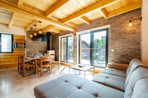 A modern interior with a wooden ceiling, stone wall, and a dining area with a table and chairs. - Apartment 'Agréable Chalet 3 Étoiles 3' with Mountain View, Wi-Fi and Air Conditioning (Courchevel)