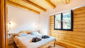 Ein Zimmer mit Holzwandverkleidung, einem Bett, einem Vorhangfenster und einer Wandleuchte.