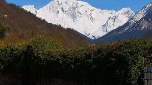 Eine Berglandschaft mit schneebedeckten Gipfeln und einer Steinmauer mit einem Hinweisschild.