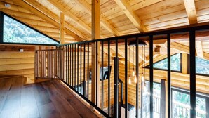A wooden interior with a balcony, large windows, and a staircase.